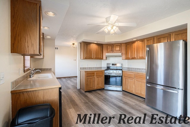 kitchen with sink, ceiling fan, a textured ceiling, appliances with stainless steel finishes, and wood-type flooring