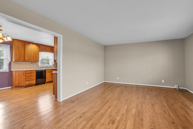 unfurnished living room with sink, light hardwood / wood-style flooring, built in desk, and a notable chandelier