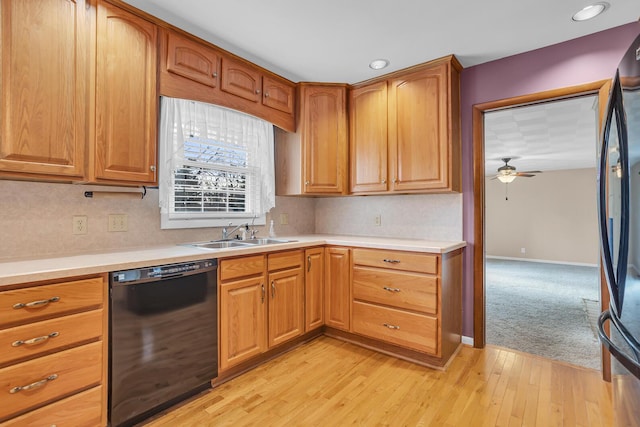 kitchen with ceiling fan, sink, black dishwasher, light hardwood / wood-style floors, and stainless steel refrigerator