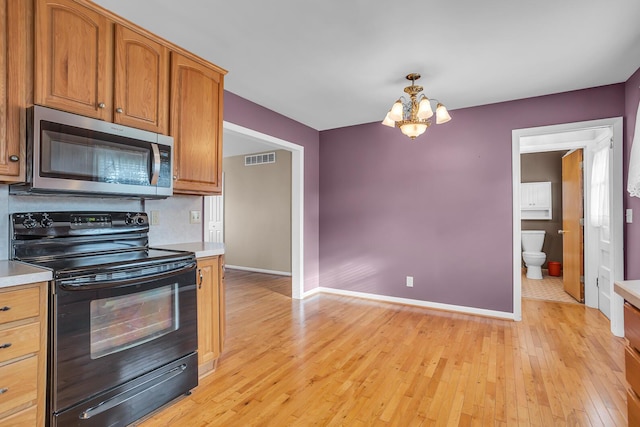 kitchen featuring electric range, decorative light fixtures, light wood-type flooring, and a chandelier