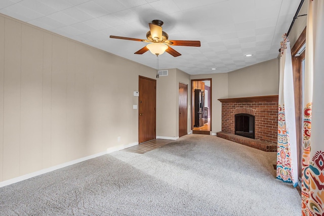 unfurnished living room with carpet, ceiling fan, and a brick fireplace