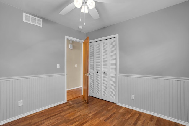 unfurnished bedroom with ceiling fan, wood-type flooring, and a closet