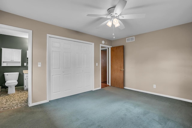 unfurnished bedroom featuring dark colored carpet, ceiling fan, connected bathroom, and a closet