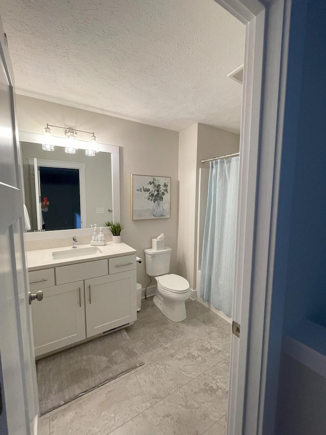 bathroom with vanity, a textured ceiling, and toilet