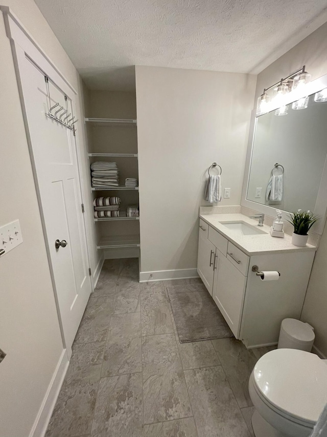 bathroom featuring vanity, a textured ceiling, and toilet