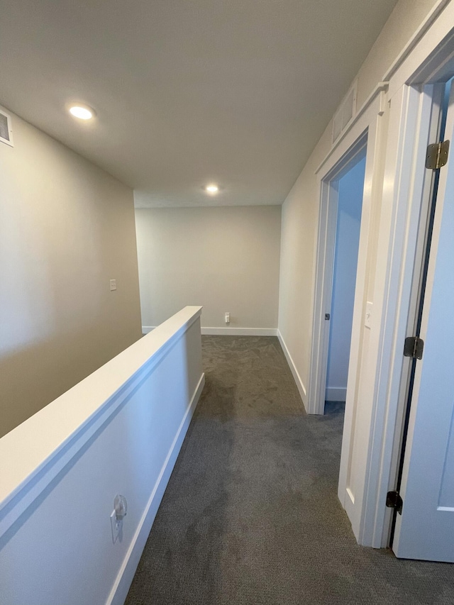 hall with dark colored carpet