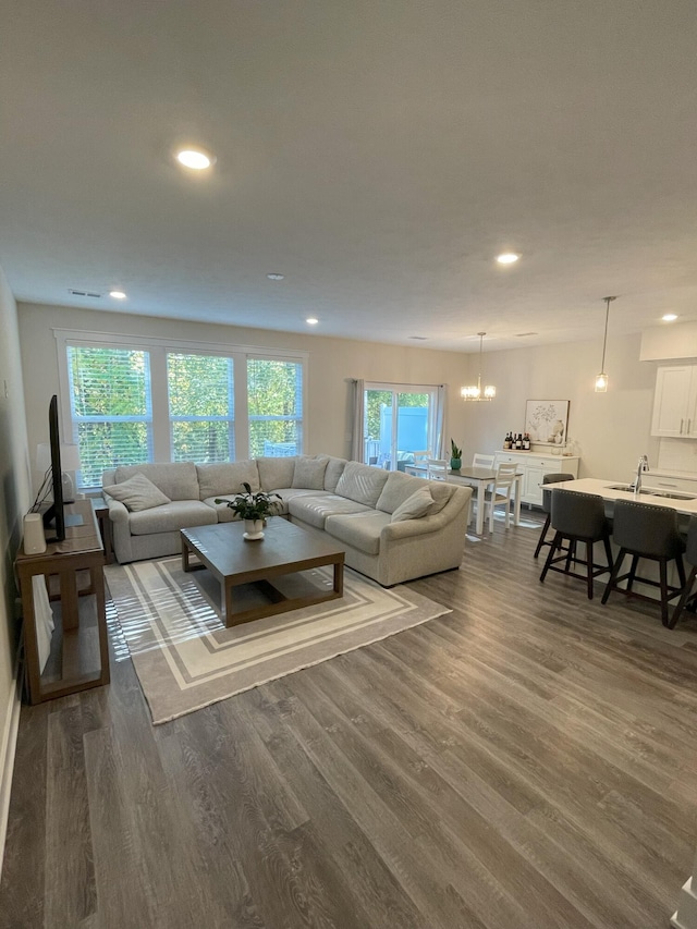 living room featuring dark hardwood / wood-style flooring, sink, and a notable chandelier