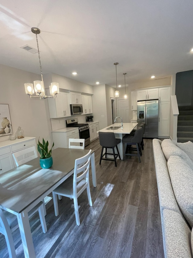 dining area with a notable chandelier, dark hardwood / wood-style floors, and sink