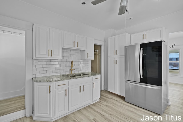 kitchen featuring white cabinets, sink, and stainless steel refrigerator