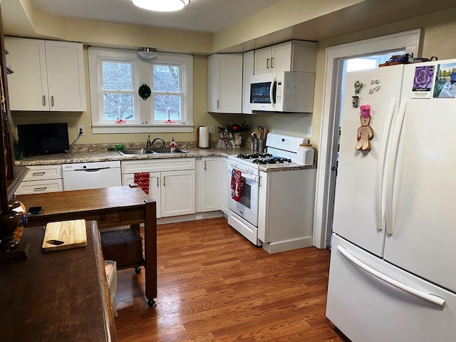 kitchen with light stone countertops, white appliances, sink, hardwood / wood-style flooring, and white cabinetry