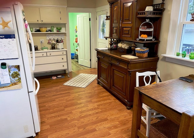 kitchen featuring dark brown cabinetry, light wood-type flooring, and white refrigerator