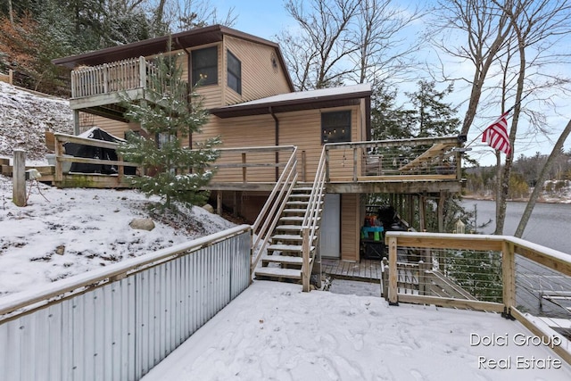 snow covered back of property featuring a wooden deck