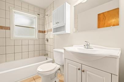 full bathroom with tile patterned flooring, vanity, tiled shower / bath combo, and toilet