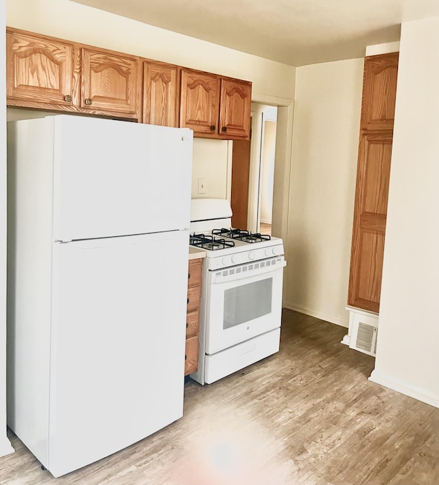 kitchen with light hardwood / wood-style floors and white appliances