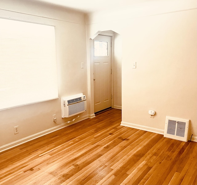 empty room featuring a wall mounted AC and wood-type flooring