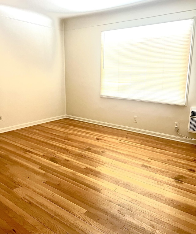 unfurnished room featuring a wall mounted air conditioner and light hardwood / wood-style flooring