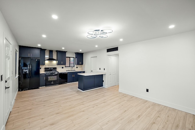 kitchen with a center island, black appliances, wall chimney range hood, sink, and light hardwood / wood-style flooring