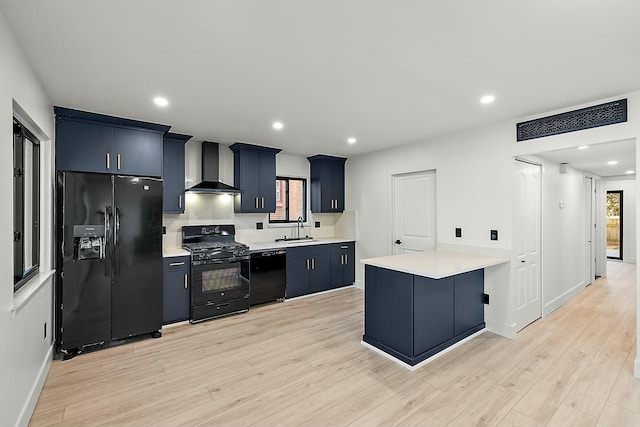 kitchen with black appliances, sink, wall chimney exhaust hood, light wood-type flooring, and a kitchen bar