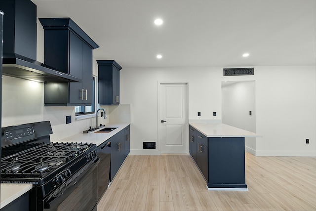 kitchen with sink, wall chimney range hood, kitchen peninsula, light hardwood / wood-style floors, and black appliances