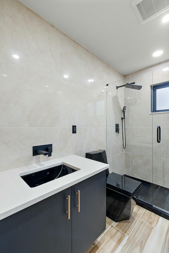 bathroom featuring vanity, an enclosed shower, and tile walls