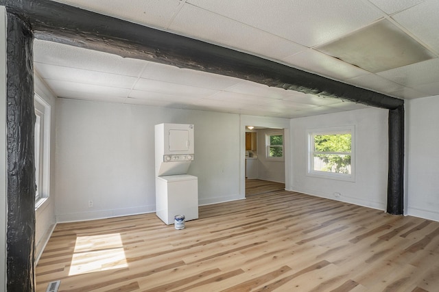 unfurnished room featuring a paneled ceiling, light hardwood / wood-style floors, and stacked washer and dryer