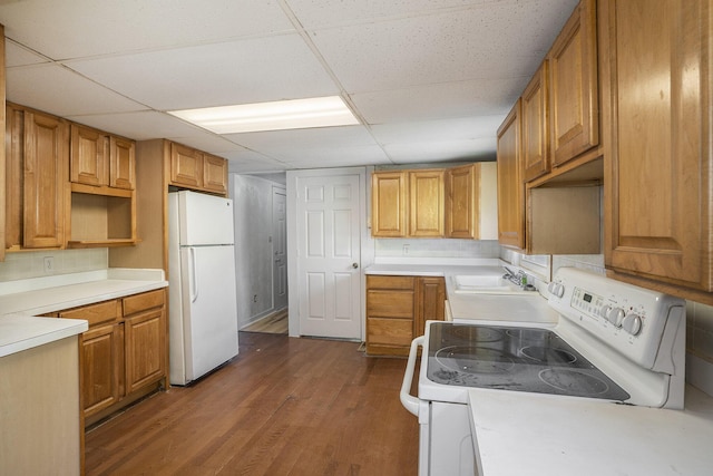 kitchen with backsplash, a drop ceiling, white appliances, sink, and hardwood / wood-style floors