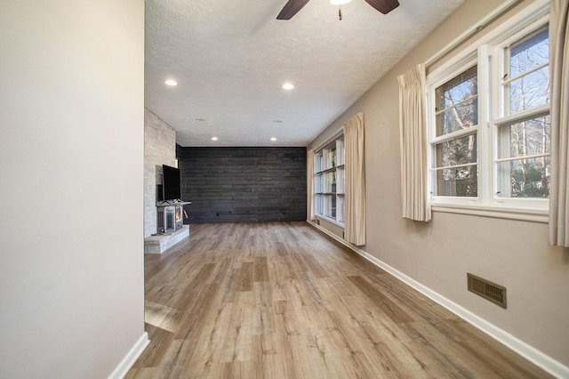 unfurnished living room featuring ceiling fan, light hardwood / wood-style floors, and a textured ceiling