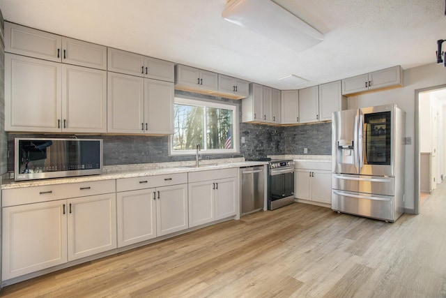 kitchen with decorative backsplash, stainless steel appliances, light hardwood / wood-style floors, and sink