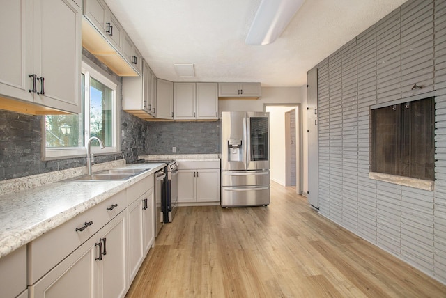 kitchen with decorative backsplash, stainless steel fridge, sink, and light hardwood / wood-style flooring