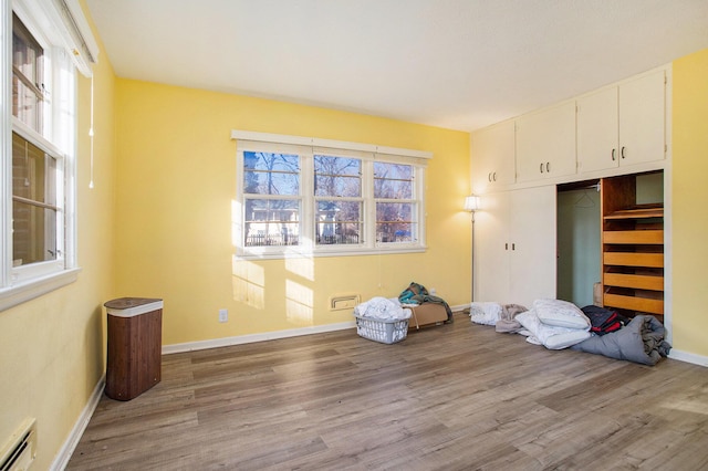 unfurnished bedroom featuring hardwood / wood-style floors, a closet, and a baseboard radiator