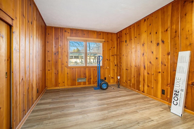 exercise area featuring wood walls and light hardwood / wood-style floors