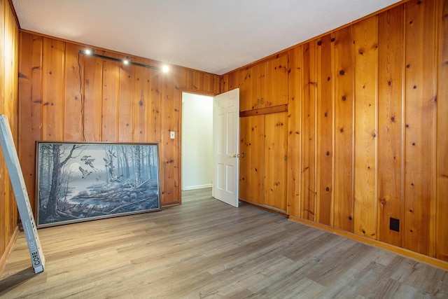 unfurnished room with wood walls and light hardwood / wood-style floors