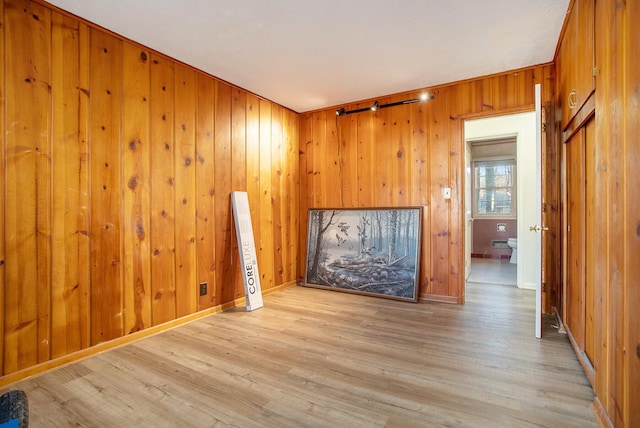 empty room with wooden walls and light hardwood / wood-style flooring