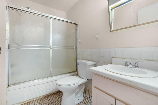 full bathroom with vanity, tile walls, enclosed tub / shower combo, tile patterned flooring, and toilet