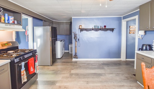 kitchen featuring gray cabinetry, black gas range oven, range hood, stainless steel refrigerator, and washer / clothes dryer