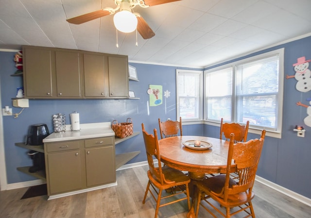 dining space with ceiling fan, light wood-type flooring, and ornamental molding