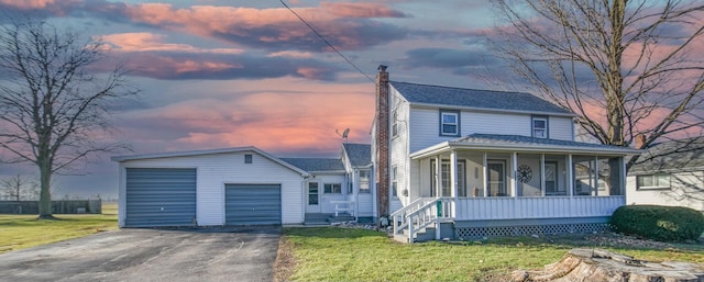 view of front of property featuring an outbuilding, a yard, a garage, and a sunroom