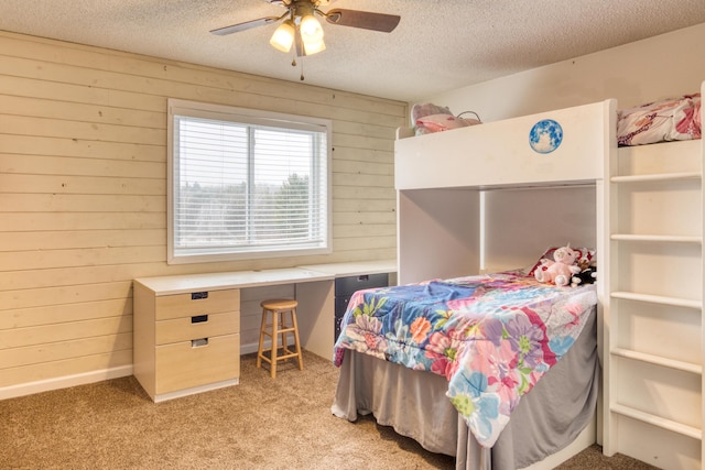 carpeted bedroom featuring a textured ceiling, ceiling fan, and wood walls