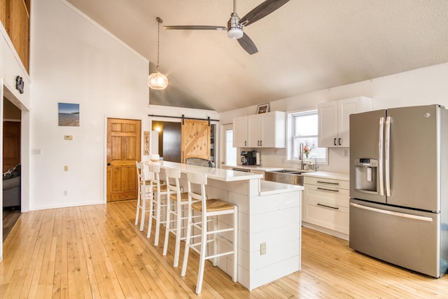 kitchen with a center island, a barn door, stainless steel fridge with ice dispenser, and white cabinetry