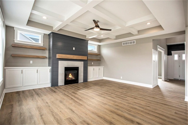 unfurnished living room with a tile fireplace, a wealth of natural light, ceiling fan, and light hardwood / wood-style floors