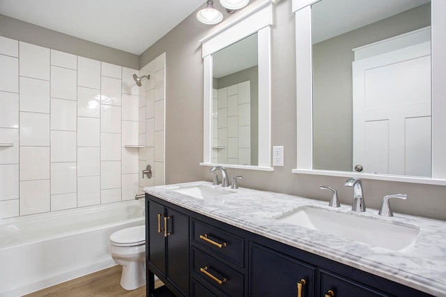 full bathroom featuring hardwood / wood-style floors, vanity, tiled shower / bath combo, and toilet