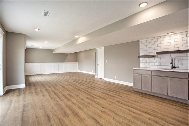 unfurnished living room featuring light wood-type flooring and sink