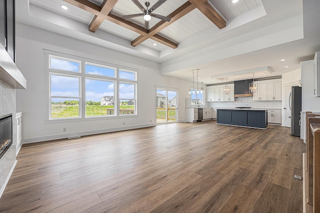 3545 Conrail Dr, Byron Center, MI 49315 - unfurnished living room with a ceiling fan, beamed ceiling, dark wood-type flooring, a glass covered fireplace, and recessed lighting