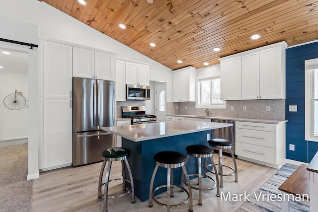 kitchen featuring white cabinetry, a center island, stainless steel appliances, lofted ceiling, and wood ceiling