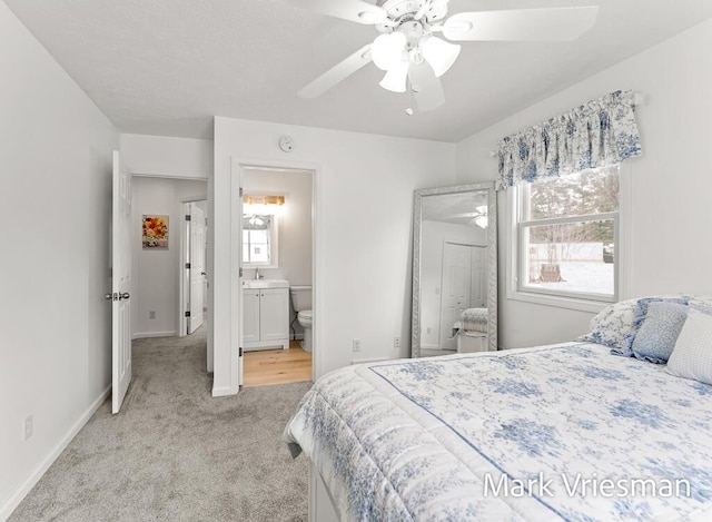 bedroom with light colored carpet, ceiling fan, and ensuite bathroom