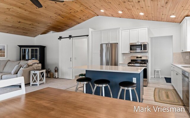 kitchen with white cabinets, a breakfast bar area, tasteful backsplash, a kitchen island, and stainless steel appliances