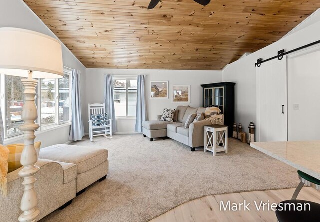 living room with vaulted ceiling, ceiling fan, wood-type flooring, a barn door, and wooden ceiling