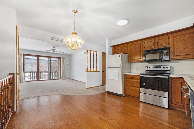 kitchen with white fridge, decorative light fixtures, electric stove, ceiling fan with notable chandelier, and light wood-type flooring