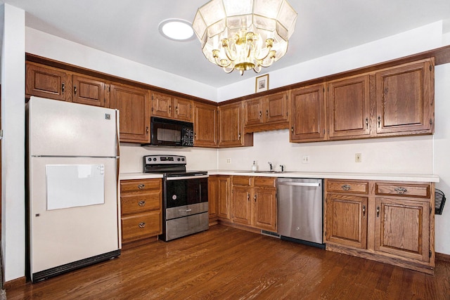 kitchen with sink, dark hardwood / wood-style flooring, a chandelier, and appliances with stainless steel finishes