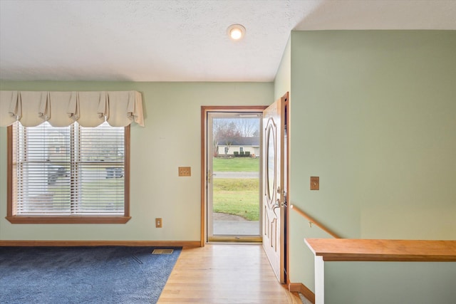 foyer entrance with plenty of natural light, a textured ceiling, and light wood-type flooring